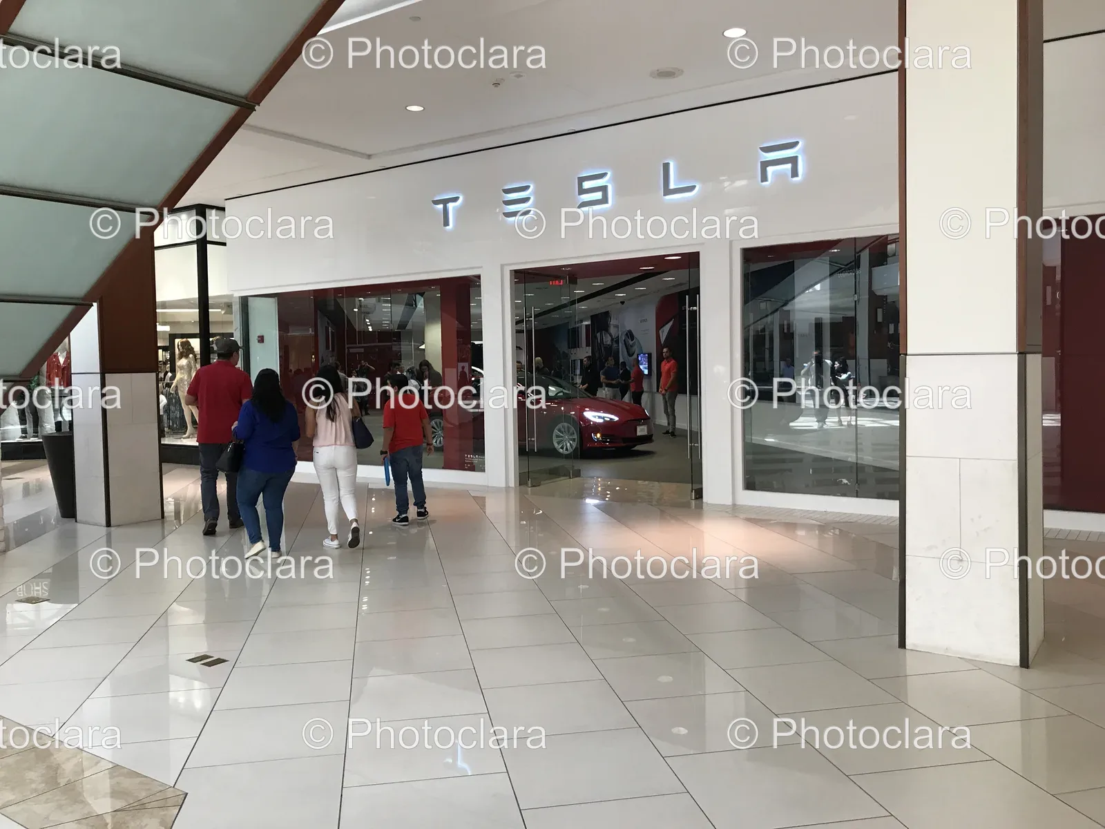 People Walking in Front of a Tesla Store
